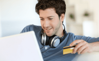 Man looking at laptop and using credit card